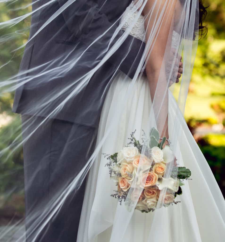 veil blowing in the wind - bride and groom embrace