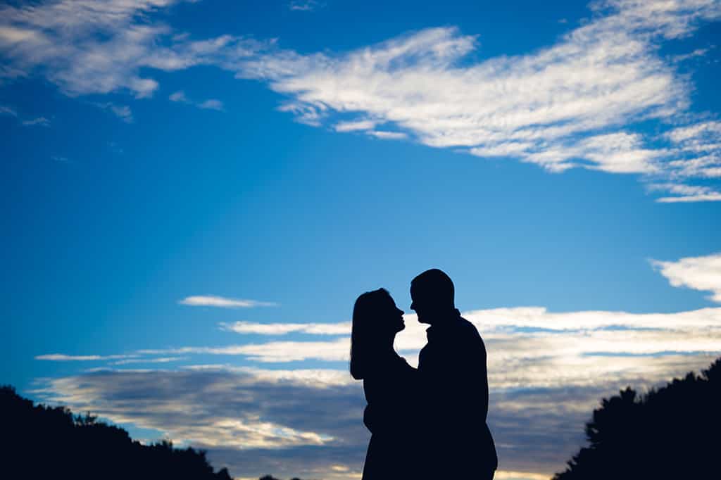 engaged couple's silhouette against blue sky