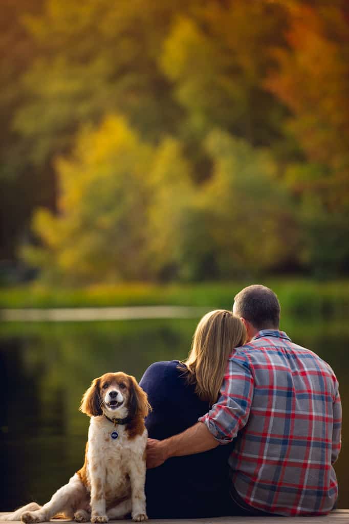 Couple on dock at lake engagement session with dog