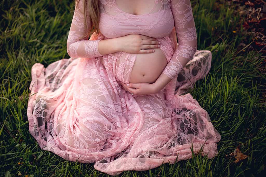 Spring maternity shoot with ethereal pink lace maternity dress belly closeup