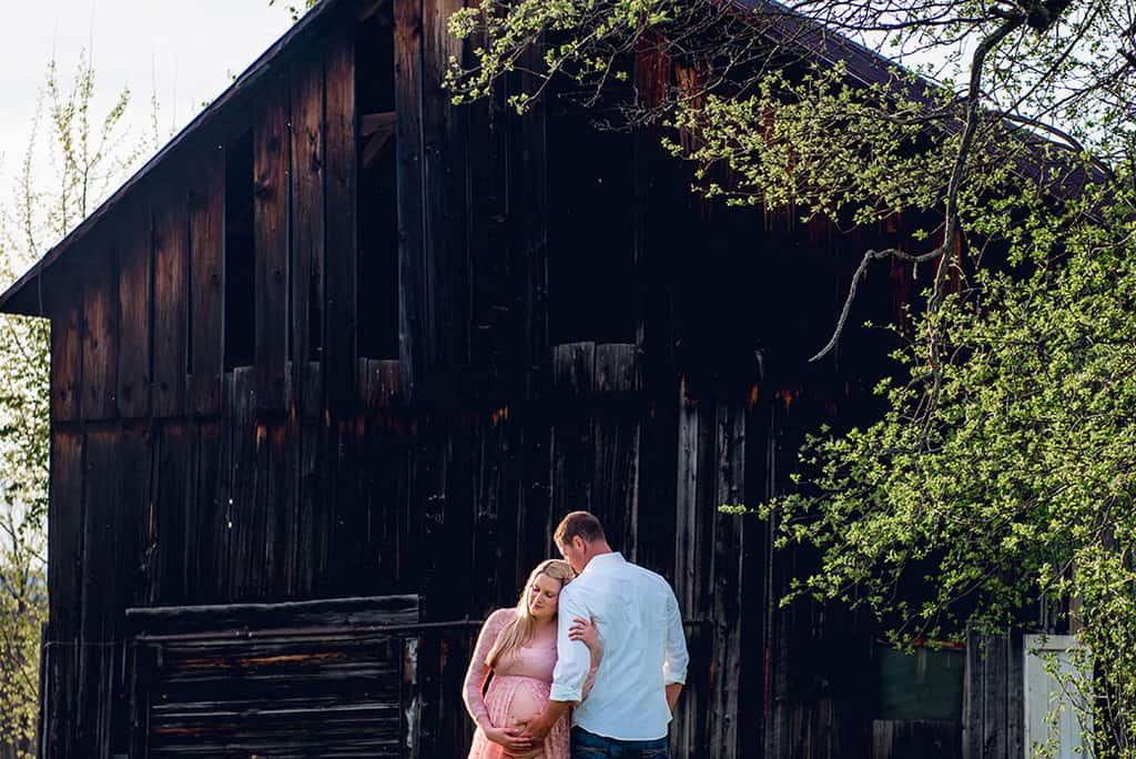 Spring maternity shoot with ethereal pink lace maternity dress at a rustic barn
