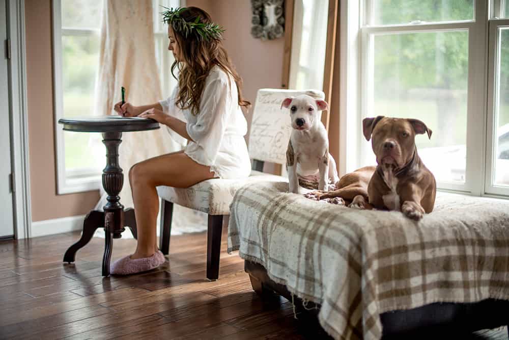 bride writing love letter to groom with her dogs close by