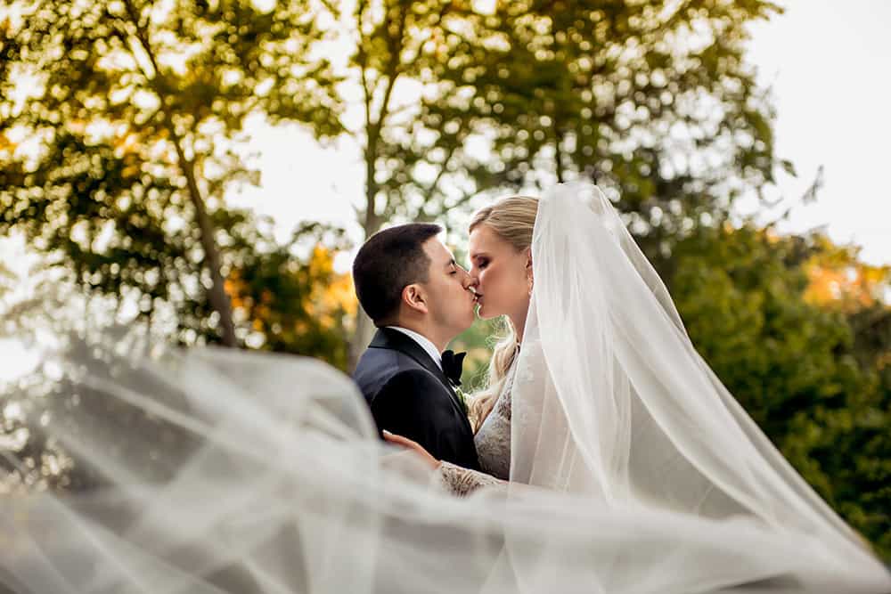 Bride and Groom kissing while veil blows around them at bedford post inn